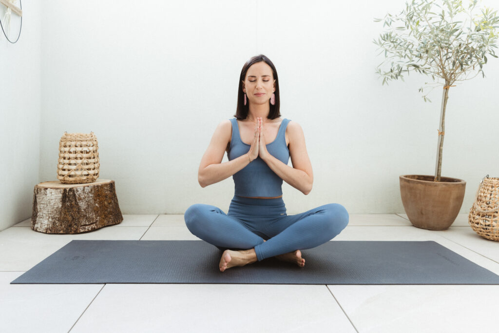 Flowing Prana Eigentümerin im Schneidersitz mit Anjali Mudra